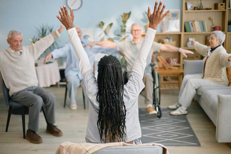Older adult and caregiver sitting together and talking in a bright, comfortable living room.